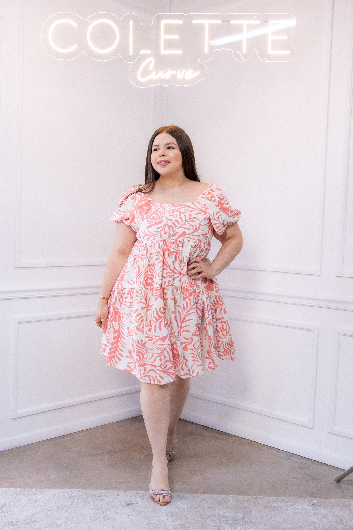 Modelo curvy usando vestido corto rosa con estampado primaveral, talla extra plus size