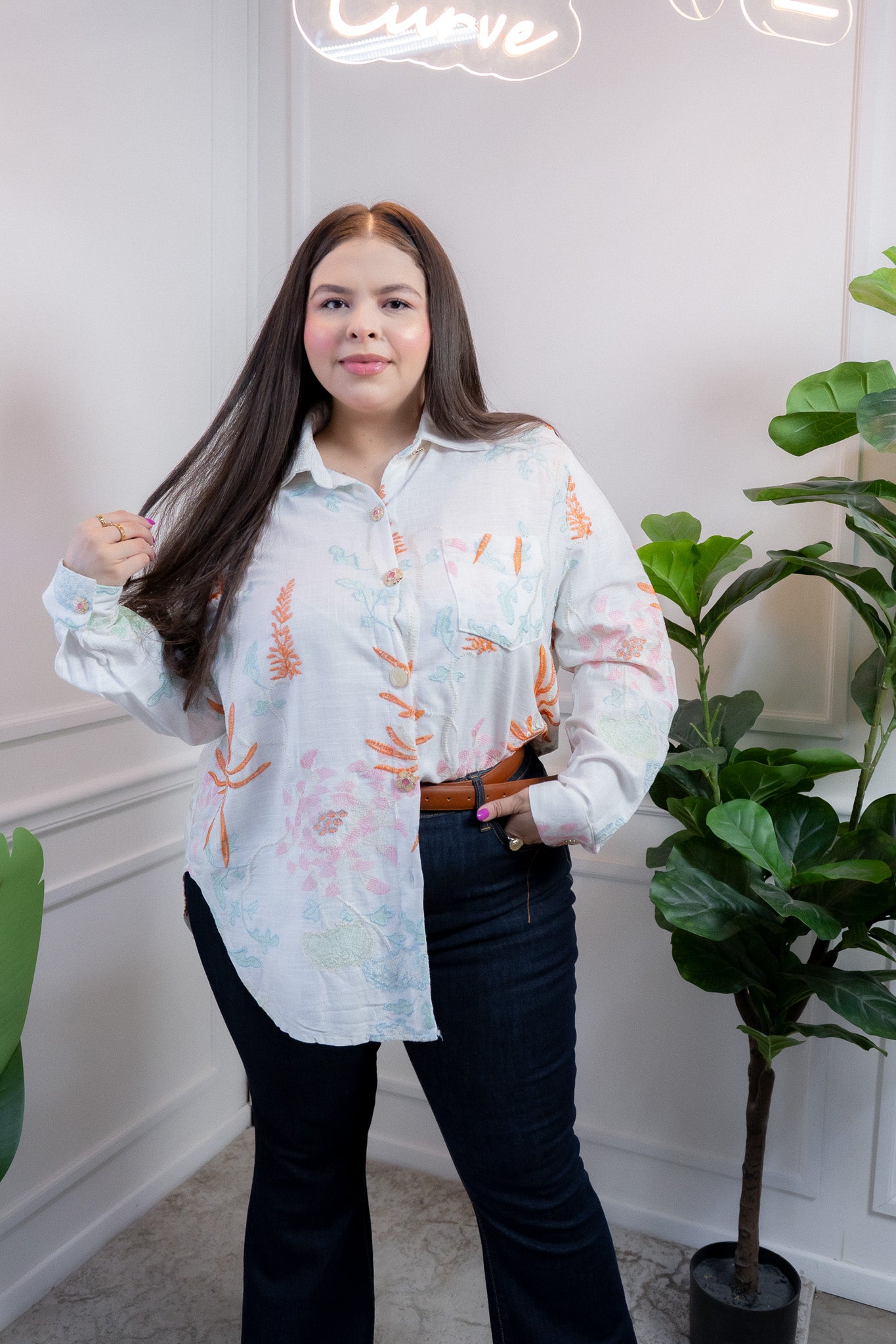 Modelo curvy usando camisa blanca con bordado floral y manga larga, talla extra plus size