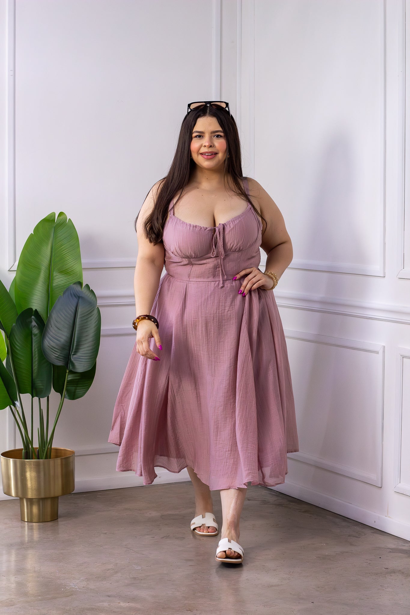 Modelo curvy usando vestido midi rosa palo con tirantes y escote en V con frunce y lazo central, tela crinkle texturizada, talla extra plus size